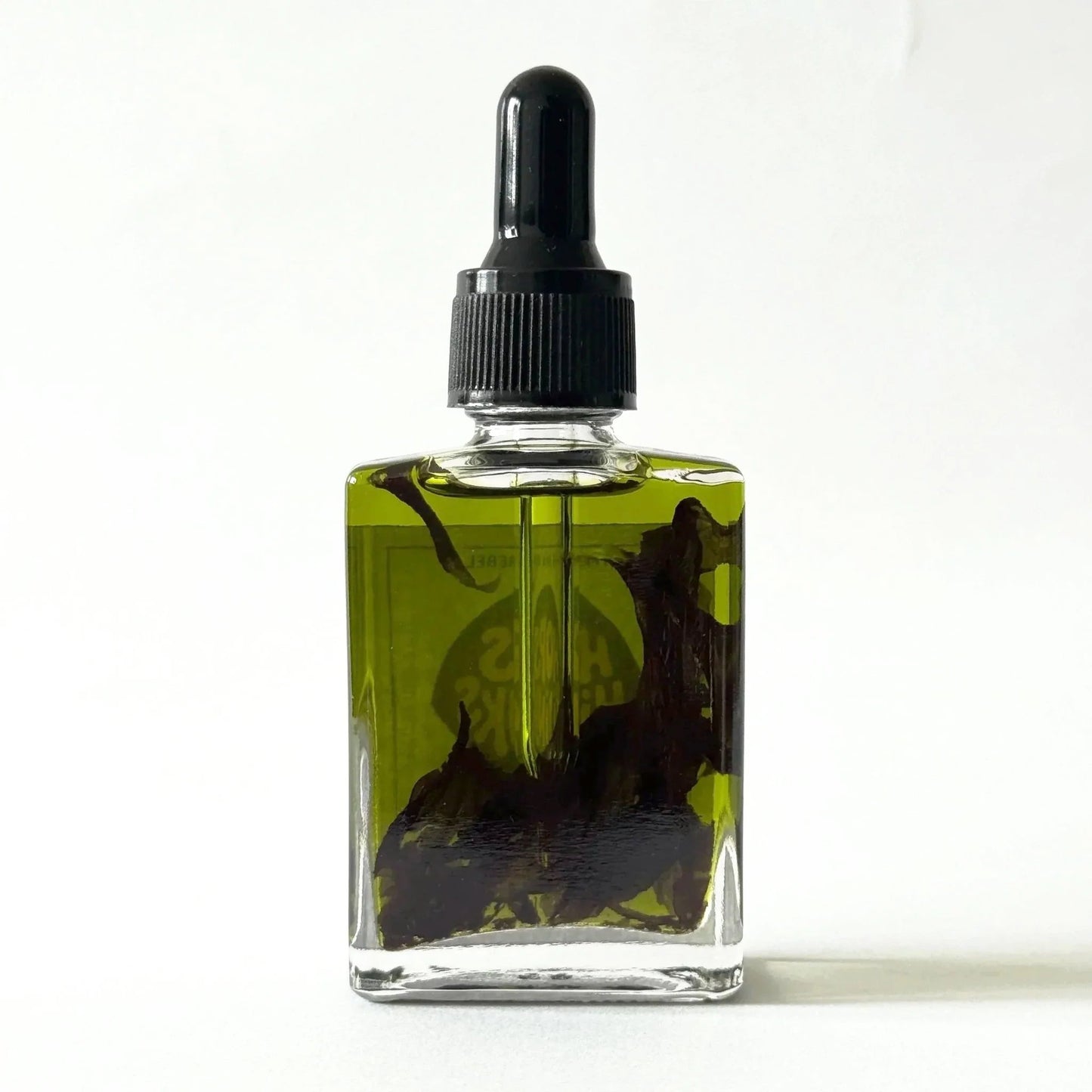Glass dropper bottle with black cap containing a green oil on a white background