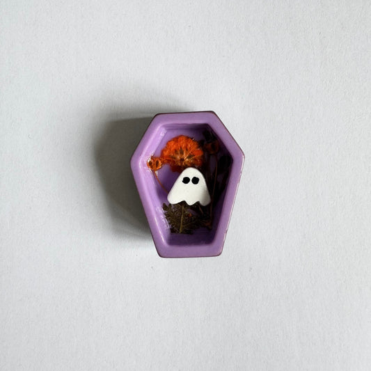 Small decorative item shaped like a purple coffin with a ghost and pumpkin on a white background