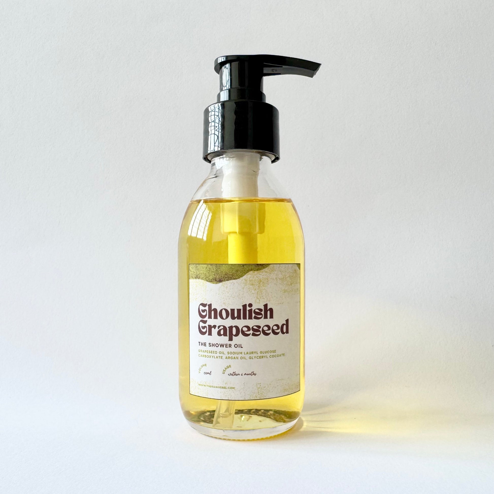 Bottle of 'Ghoulish Grapeseed' shower oil with a pump on a light background