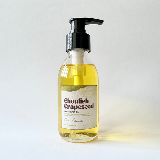 Bottle of 'Ghoulish Grapeseed' shower oil with a pump on a light background